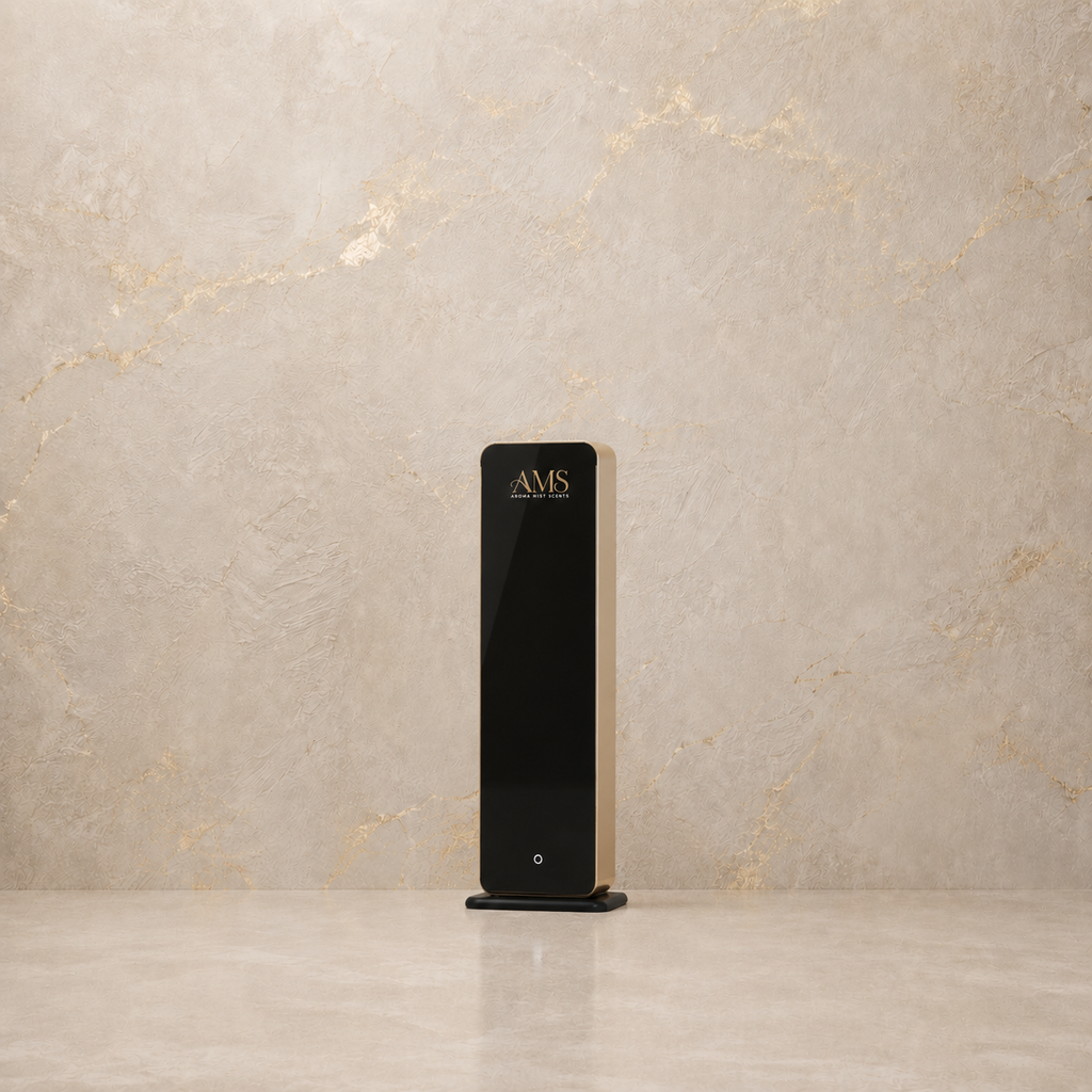 A sleek, modern black rectangular diffuser with gold lettering that reads 'AMS' on the top face, standing on a matching black base against a textured beige marble background.